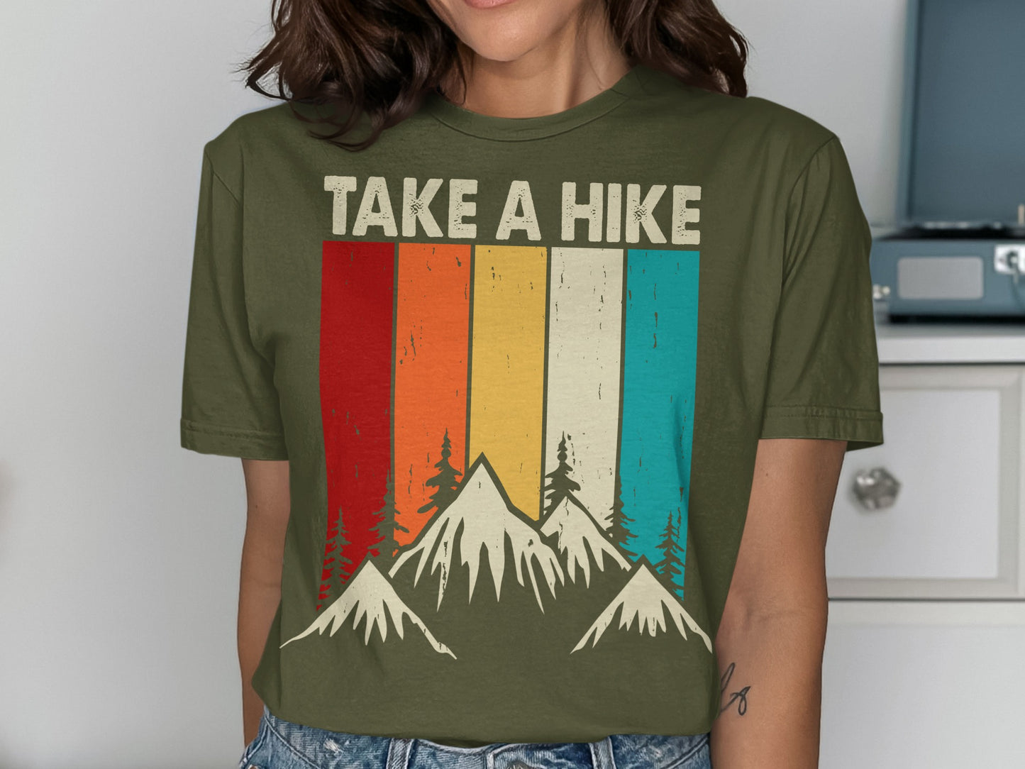 Green t-shirt with colorful stripes and mountains reading "TAKE A HIKE".