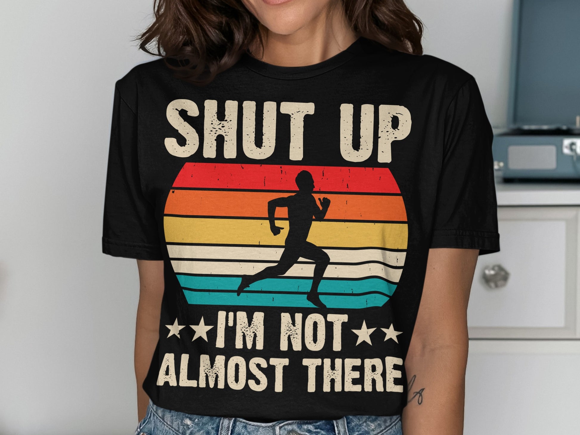 Black t-shirt with retro sunset graphic and text "SHUT UP I'M NOT ALMOST THERE".