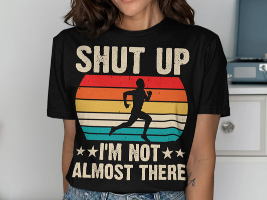 Black t-shirt with retro sunset graphic and text "SHUT UP I'M NOT ALMOST THERE".