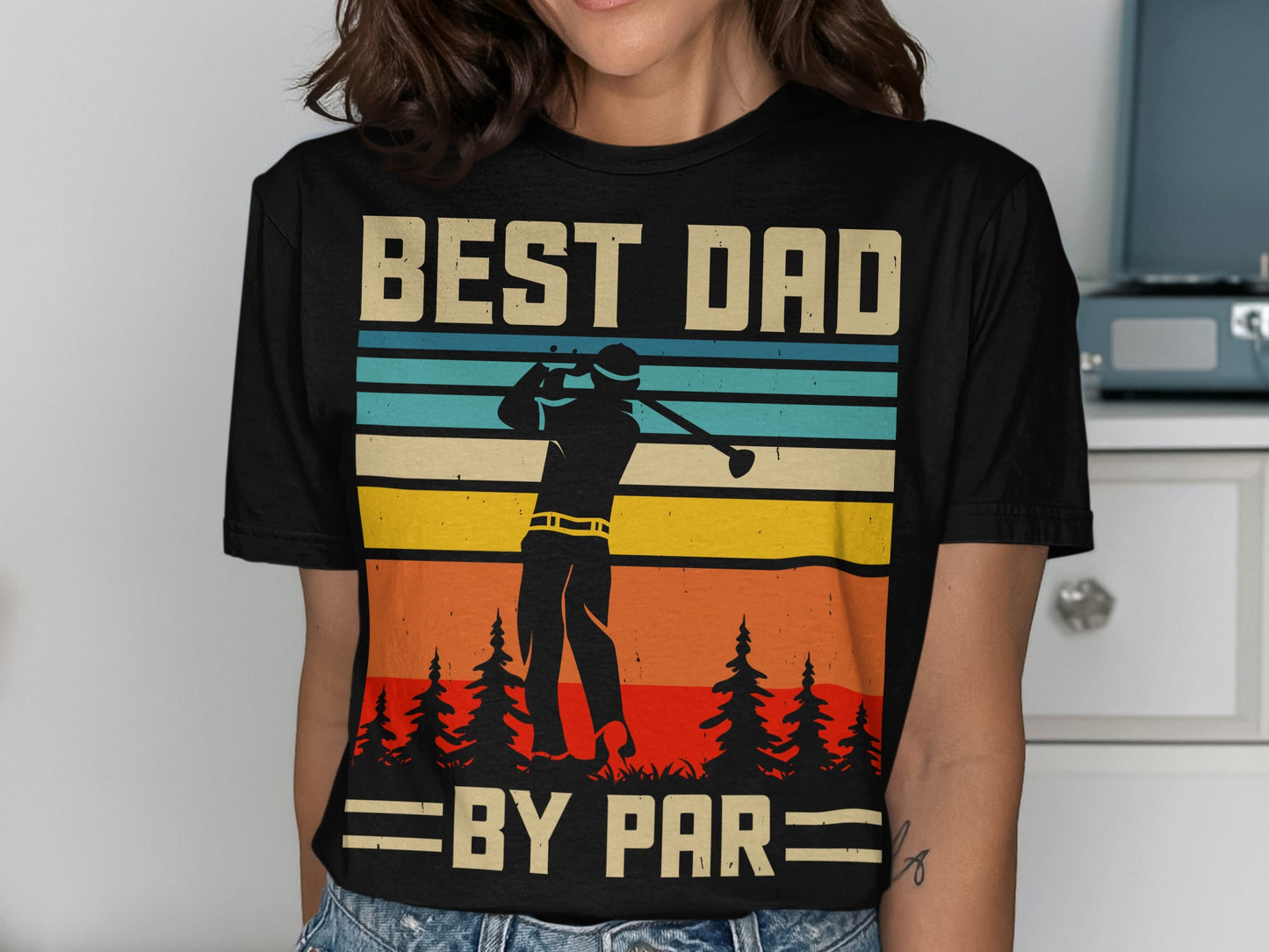 Black t-shirt with "BEST DAD BY PAR" text and golfer silhouette against striped sunset.