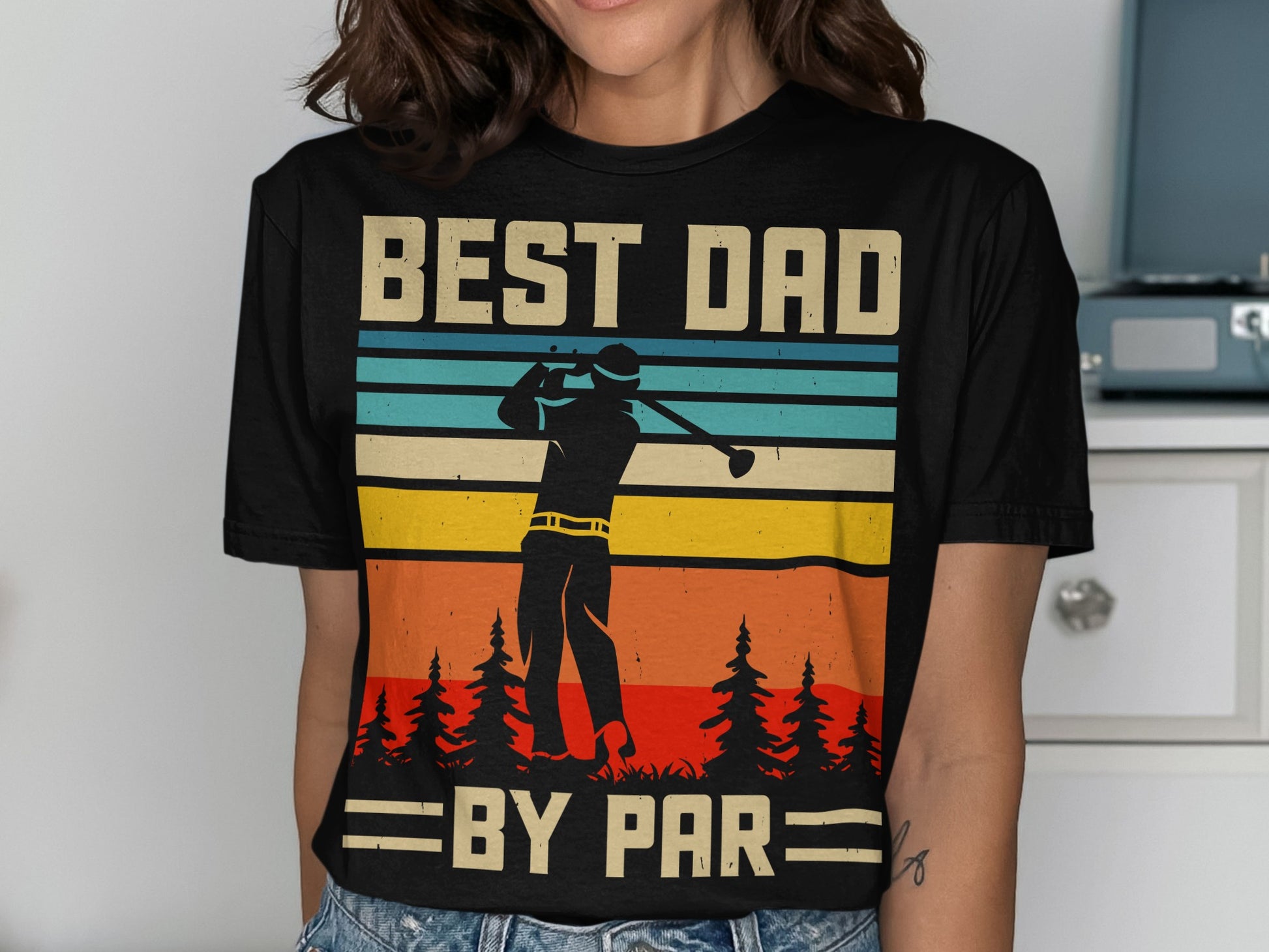 Black t-shirt with "BEST DAD BY PAR" text and golfer silhouette against striped sunset.