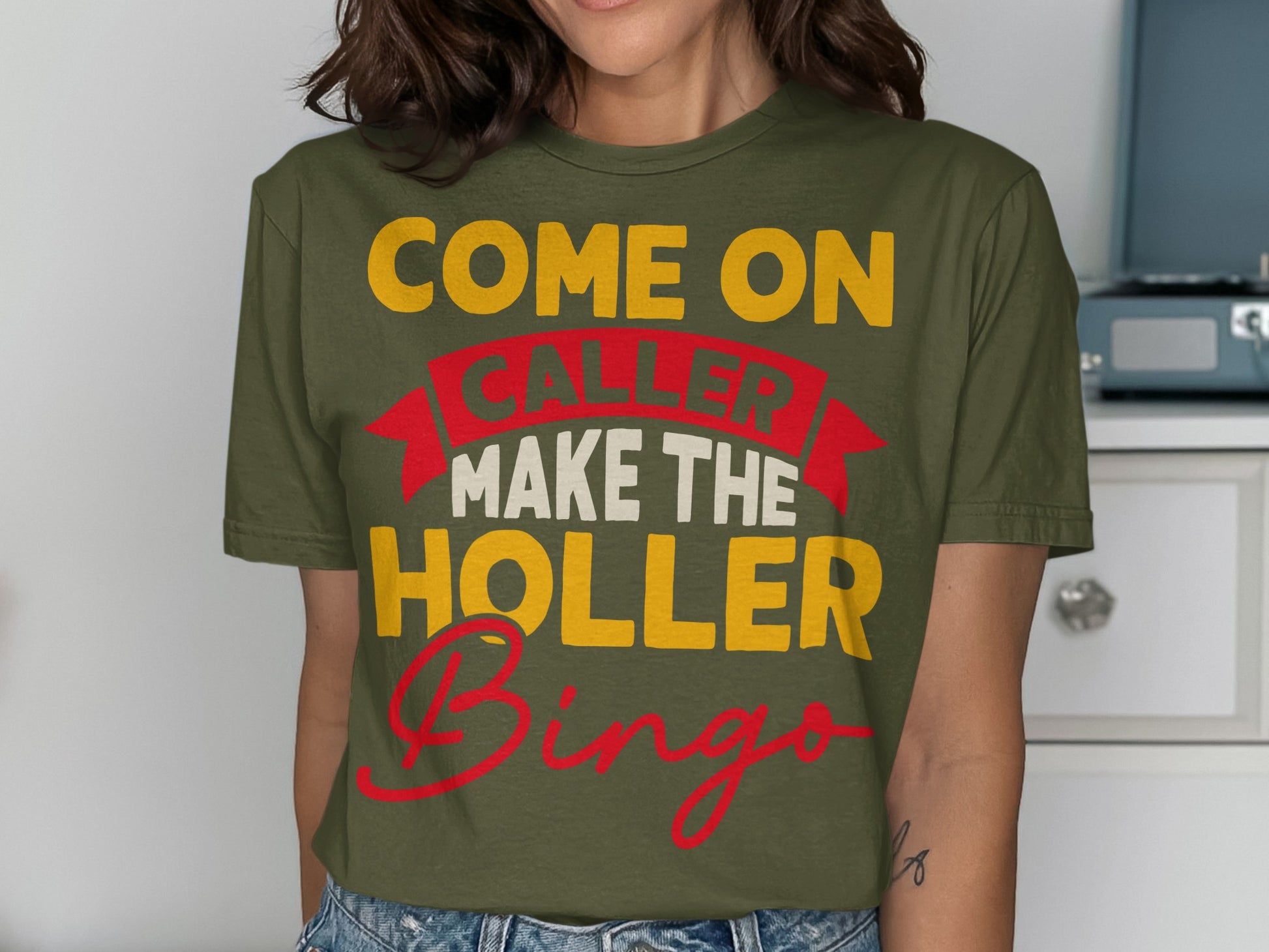 Green t-shirt with "Come On Caller Make the Holler Bingo" text in yellow and red.
