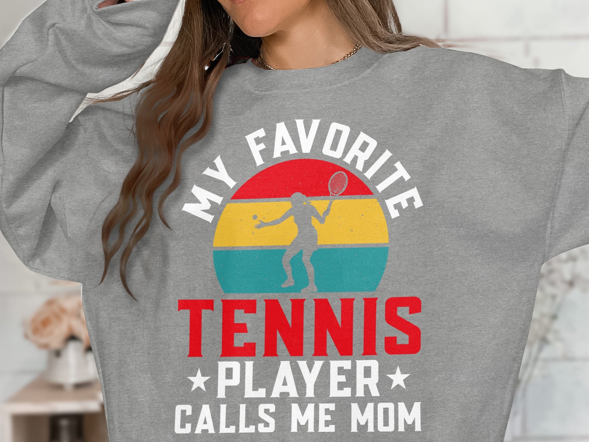 Gray sweatshirt with "MY FAVORITE TENNIS PLAYER CALLS ME MOM" text and graphic.