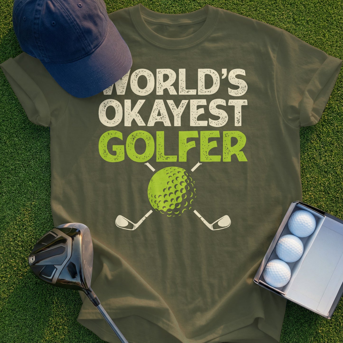 Olive t-shirt with "World's Okayest Golfer" text and a golf ball.