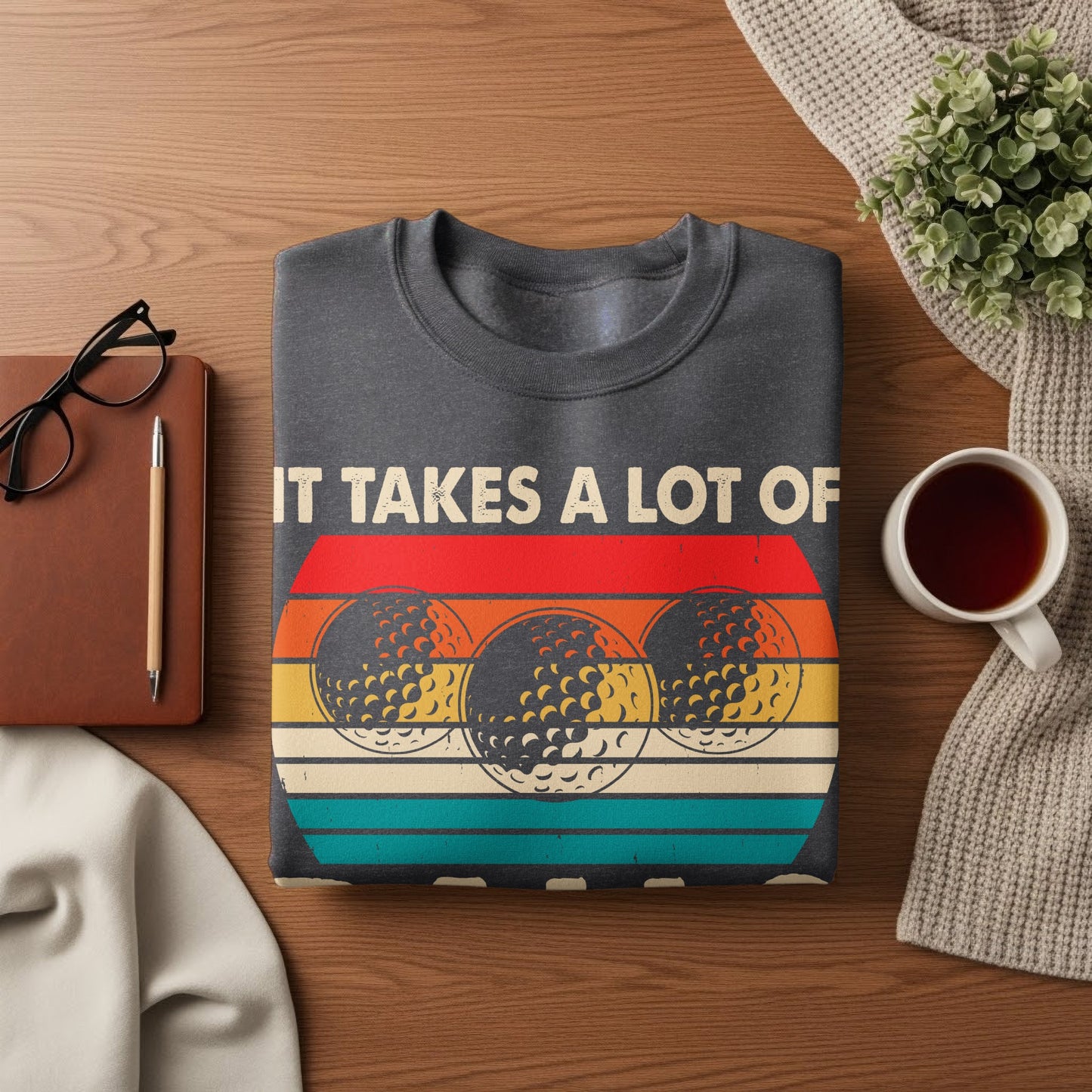 Dark gray sweatshirt with a retro design of three golf balls and text that reads "IT TAKES A LOT OF".