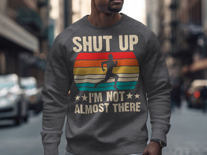 Gray sweatshirt with text "SHUT UP I'M NOT ALMOST THERE" and runner silhouette.