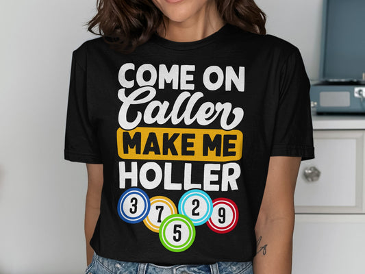 Black t-shirt with text "COME ON CALLER MAKE ME HOLLER" and colorful bingo balls.