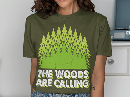 Green t-shirt with stylized pine trees and "The Woods Are Calling" text.