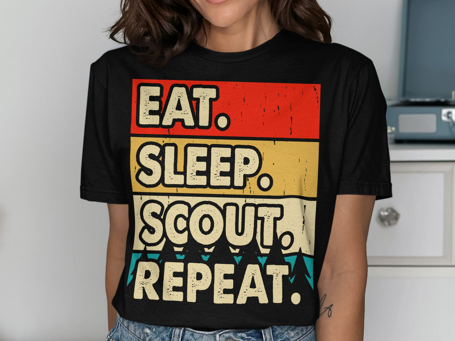 Black t-shirt with "EAT. SLEEP. SCOUT. REPEAT." in colorful stripes.