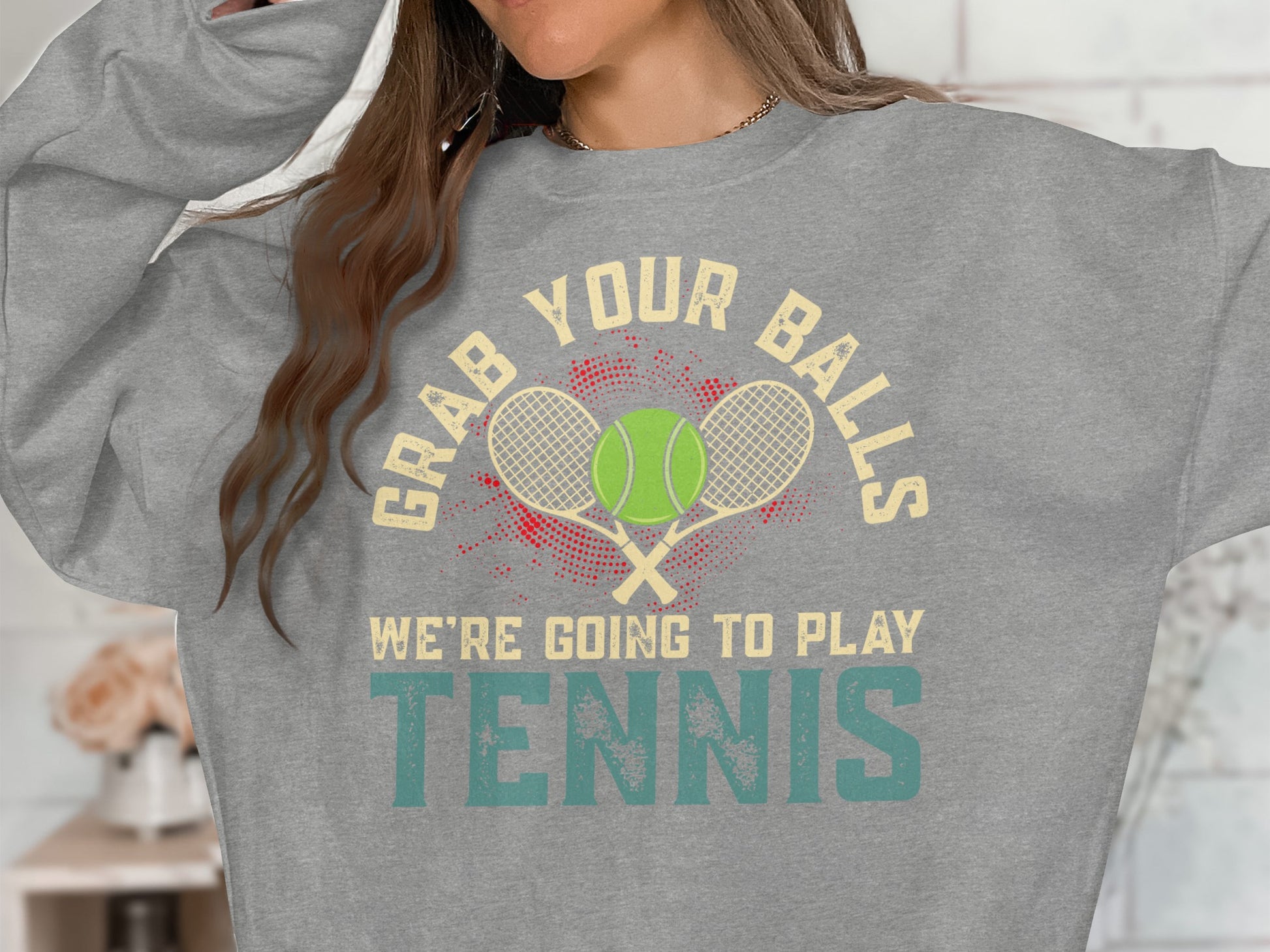Gray sweatshirt with "Grab Your Balls We're Going To Play Tennis" text and tennis balls.