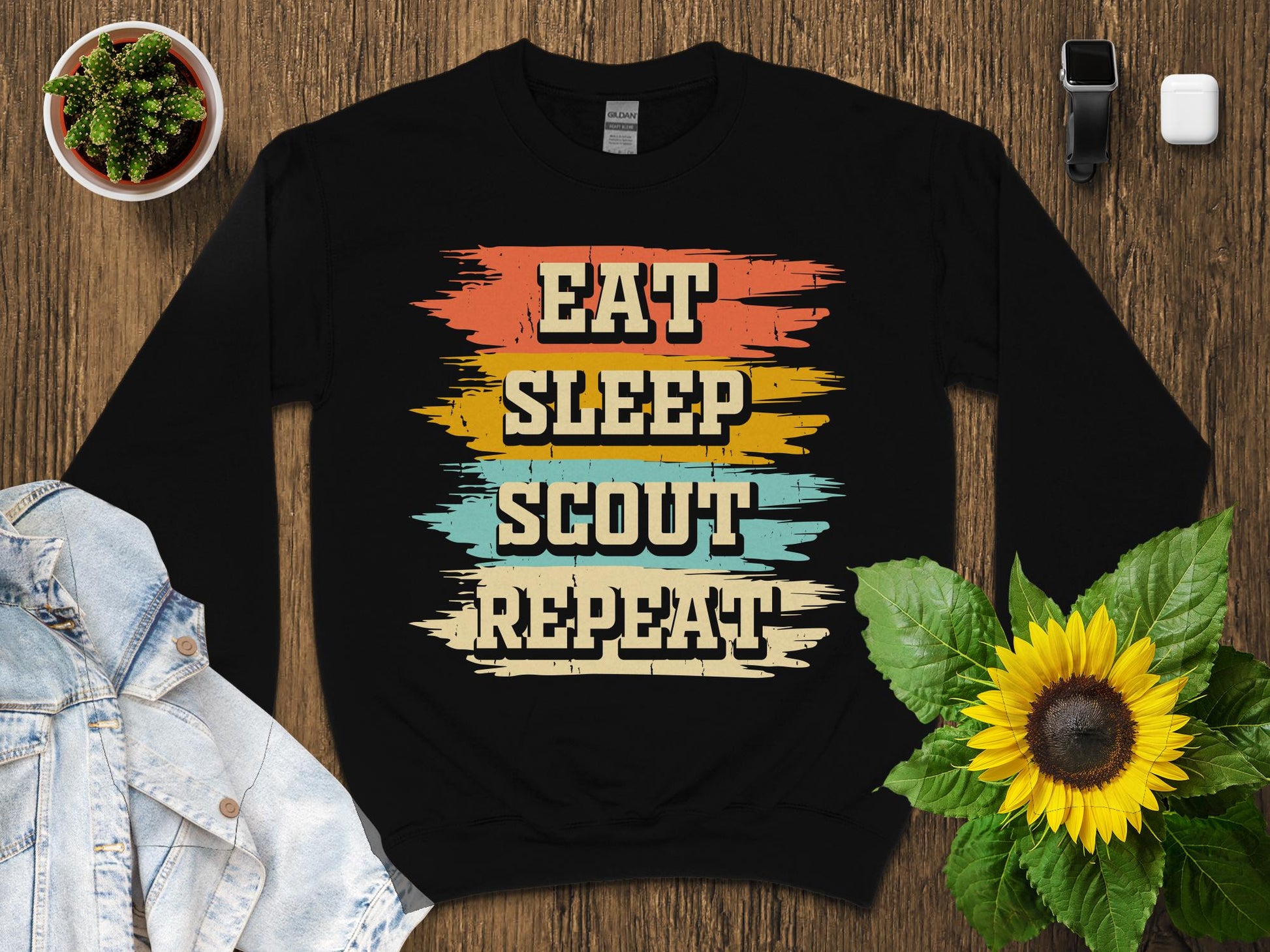 Black sweatshirt with "Eat Sleep Scout Repeat" in colorful distressed lettering.