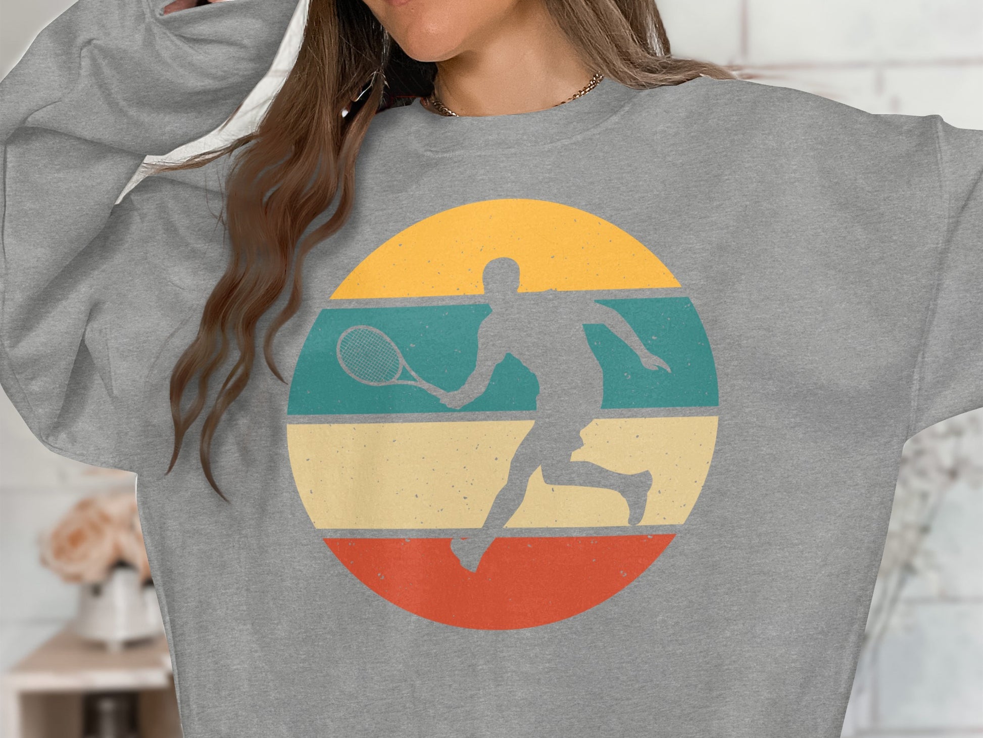 Grey sweatshirt with a circular graphic of a tennis player in retro colors.