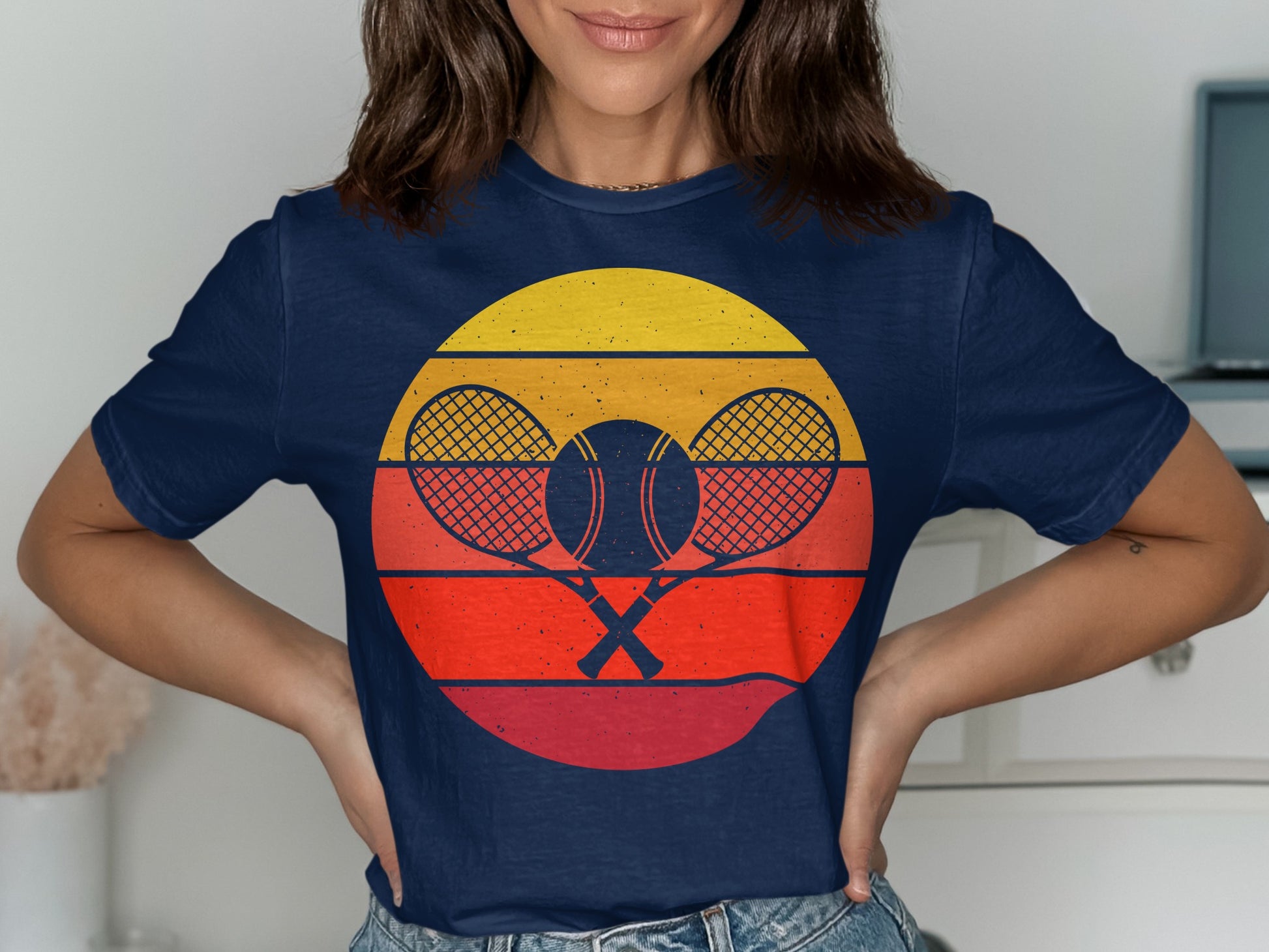 Navy t-shirt with crossed tennis rackets and ball, framed by a sunset.