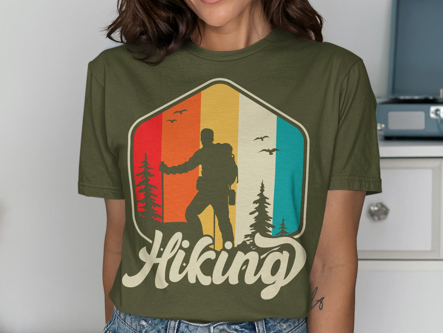 Hiking graphic on olive green t-shirt featuring a silhouette hiker and colorful stripes.