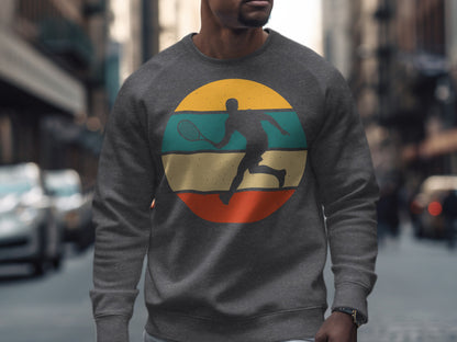 Man wearing a grey crewneck sweatshirt with a circular tennis player graphic.