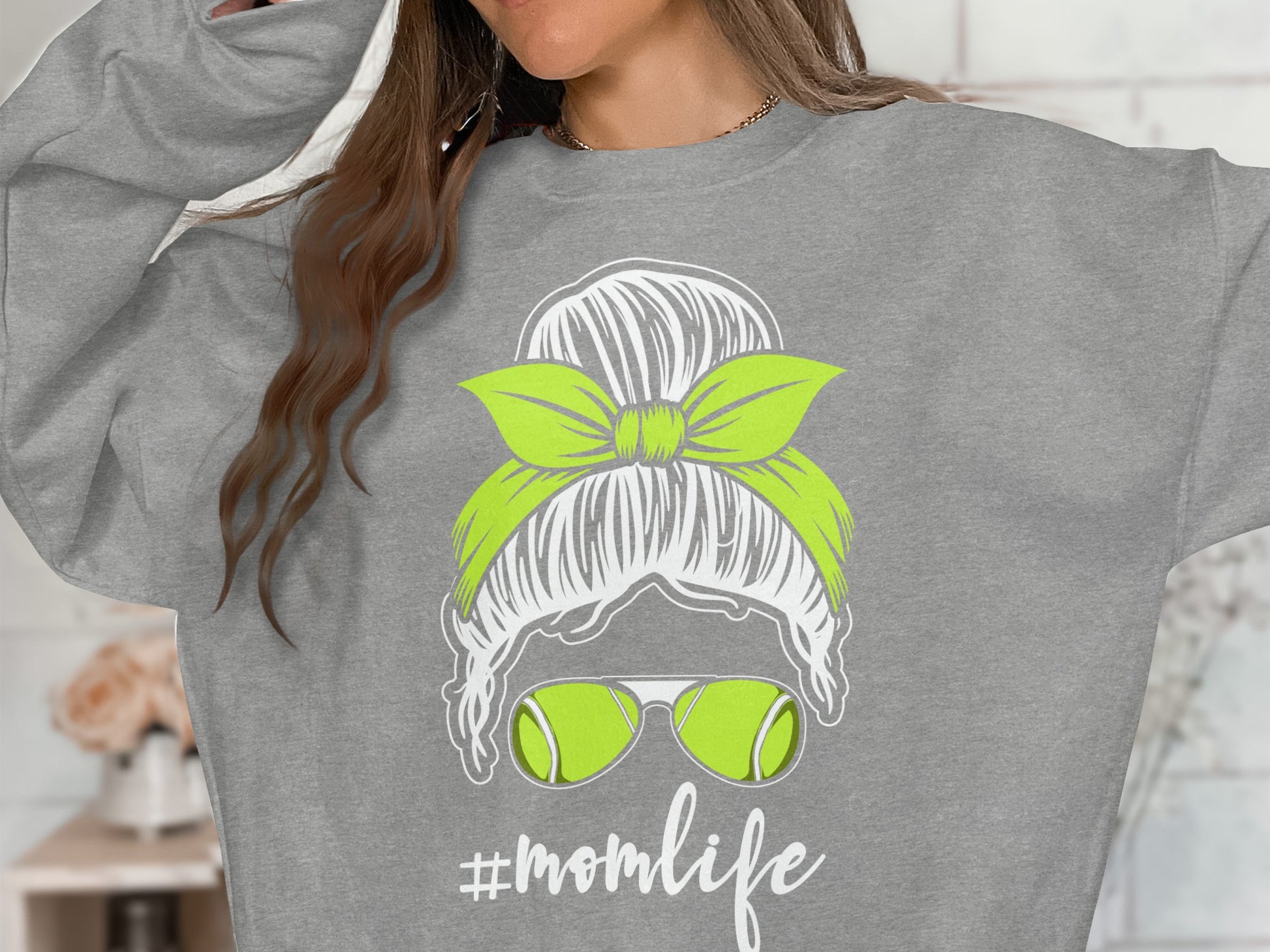 Gray sweatshirt with "momlife" graphic featuring a messy bun, sunglasses, and tennis balls.