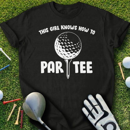 Black t-shirt with "THIS GIRL KNOWS HOW TO PAR TEE" in white text over a golf ball.