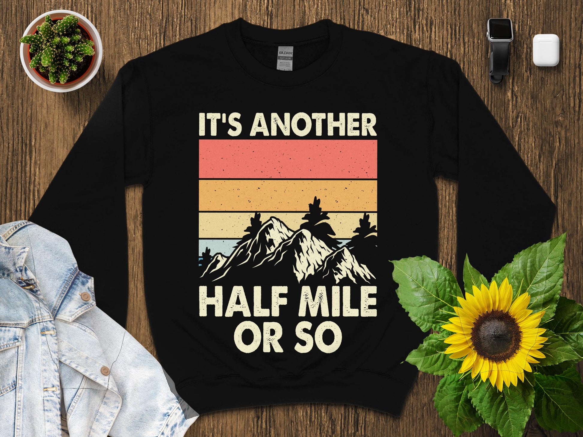 Black sweatshirt with "IT'S ANOTHER HALF MILE OR SO" and mountain graphic.