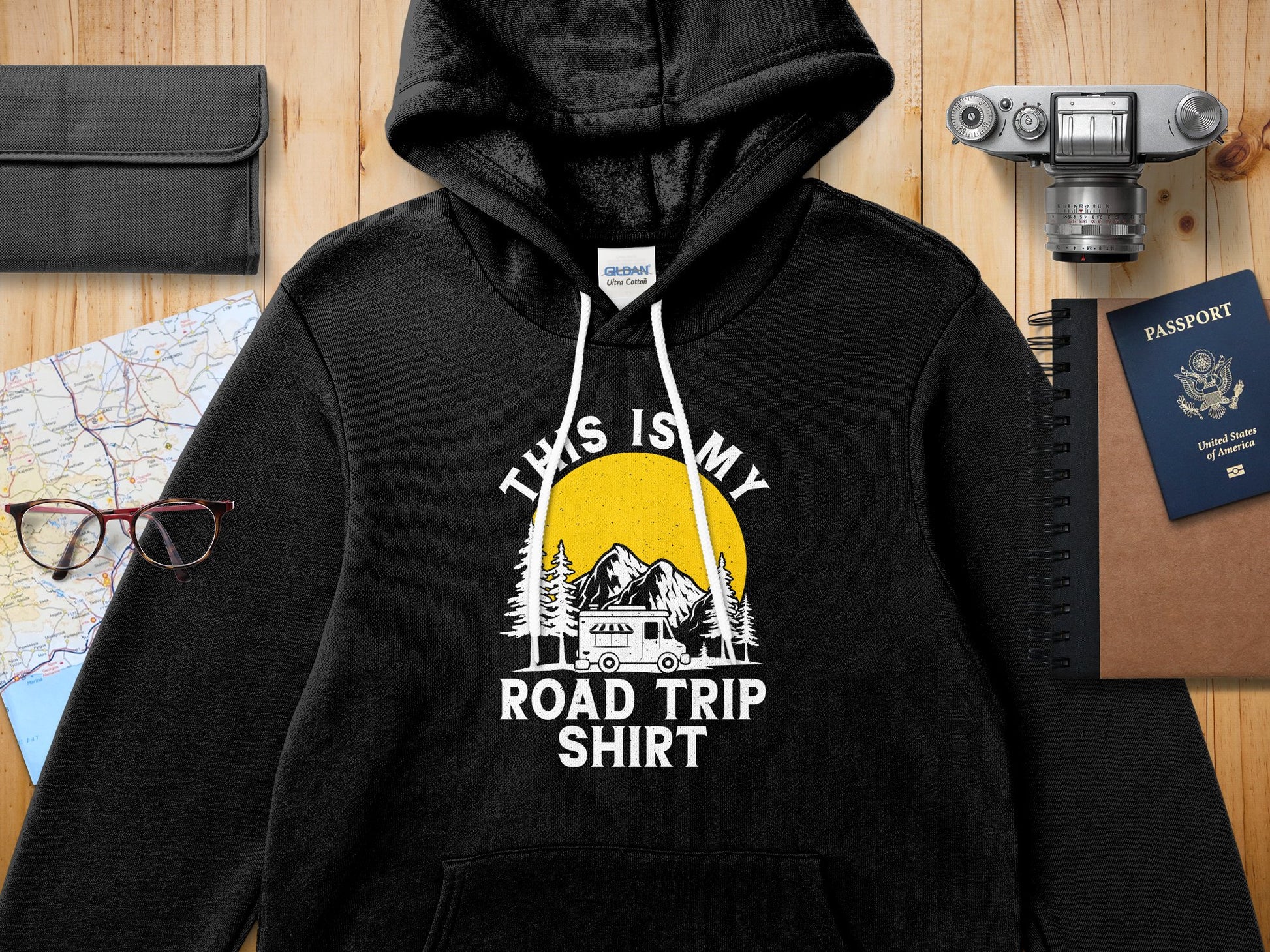 Black hoodie with "This is my Road Trip Shirt" text, mountains, and sun graphic.