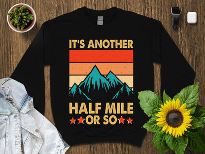 Black sweatshirt with retro mountain graphic and "It's another half mile or so" text.