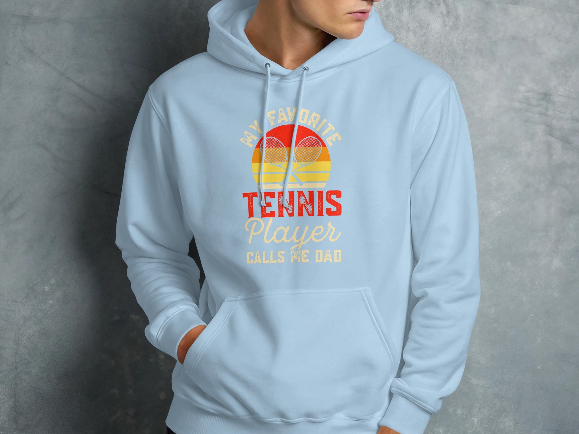 Light blue hoodie with "My Favorite Tennis Player Calls Me Dad" text and rackets.