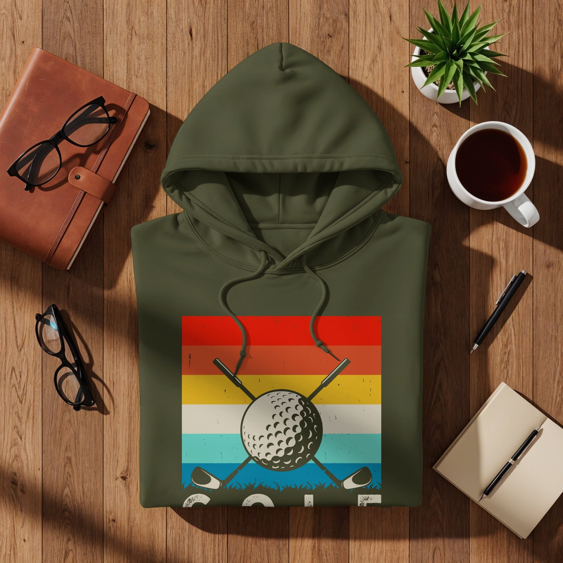 Olive green hoodie with a vintage golf graphic on a wooden surface.
