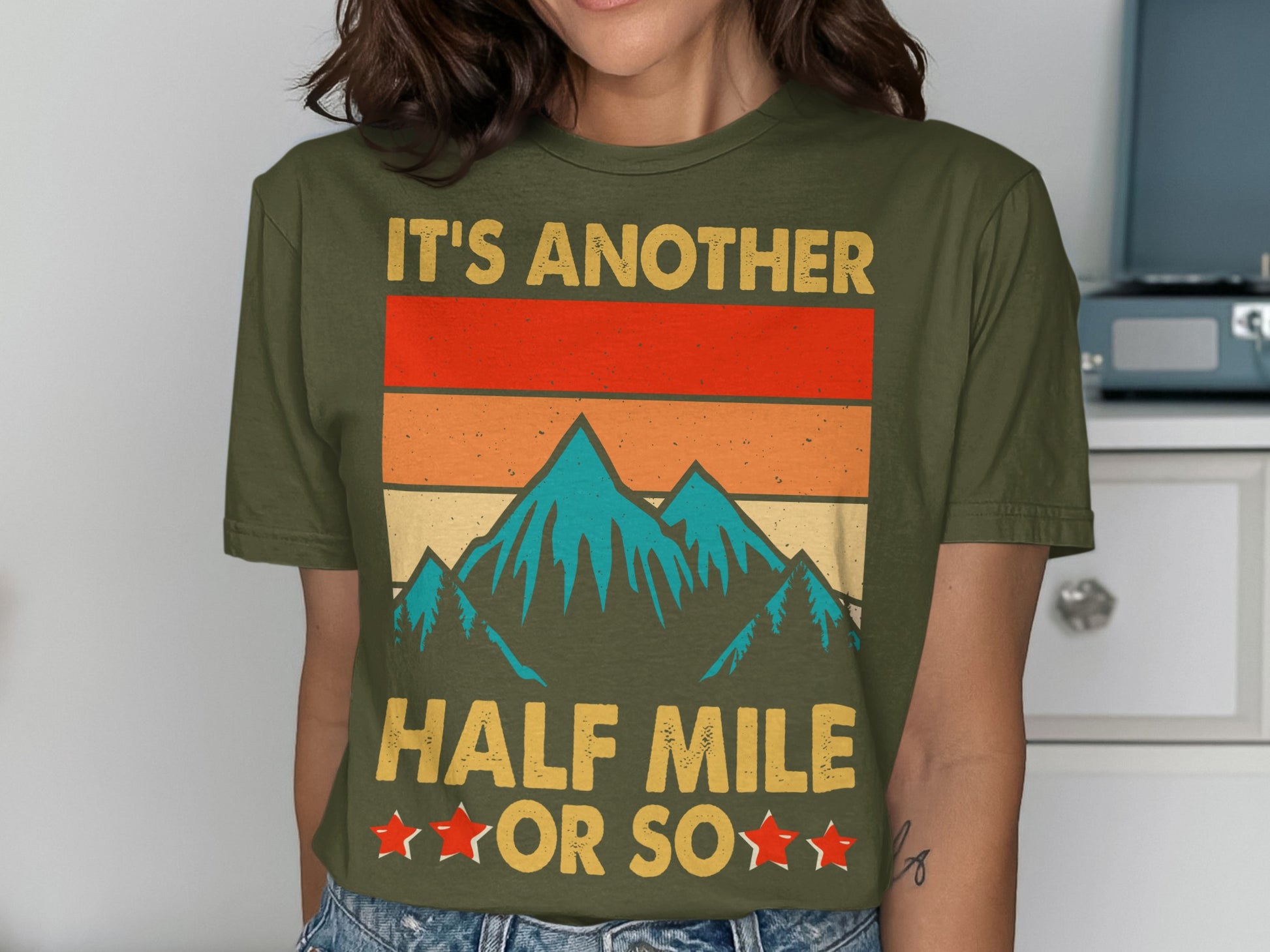 Olive t-shirt with vintage mountain graphic and text "IT'S ANOTHER HALF MILE OR SO".