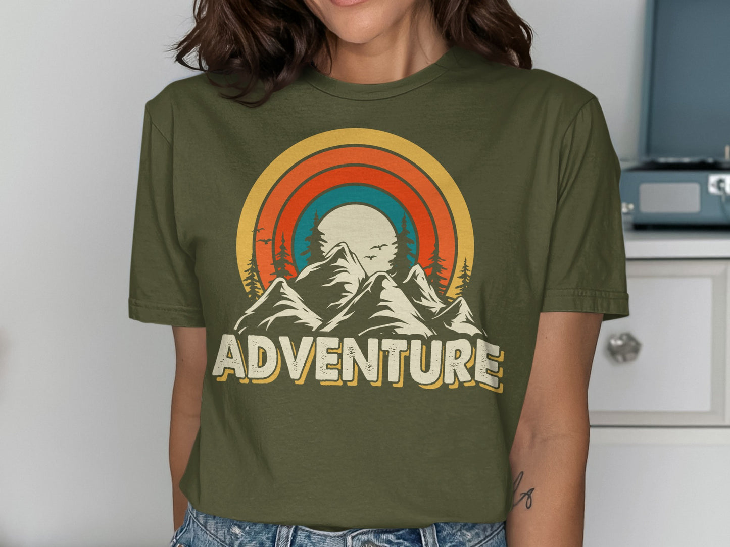 Olive green t-shirt with mountain and sunset adventure graphic.