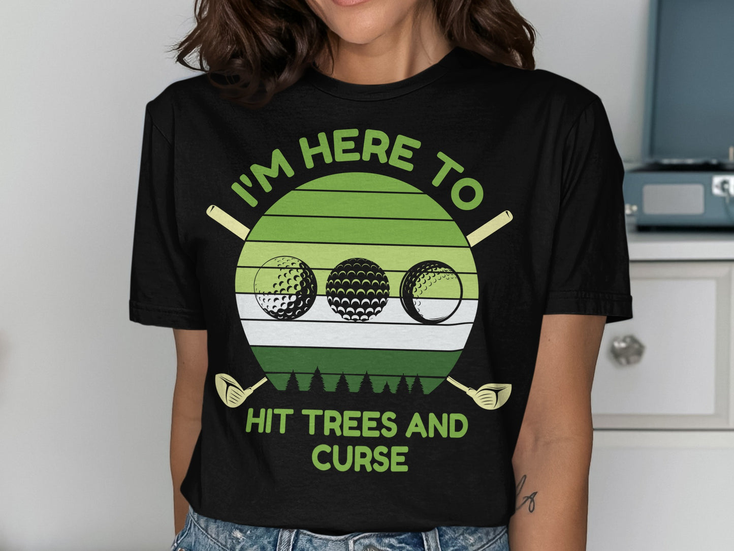 Green t-shirt with "I'm here to hit trees and curse" text and golf balls.