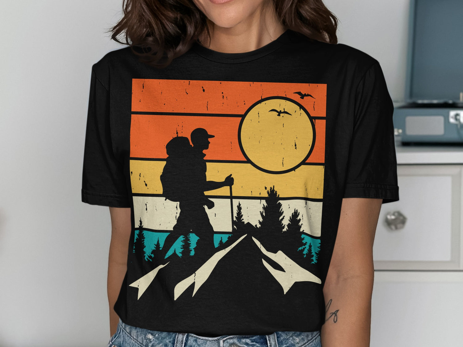 Silhouette of a hiker against a sunset with mountains and birds.