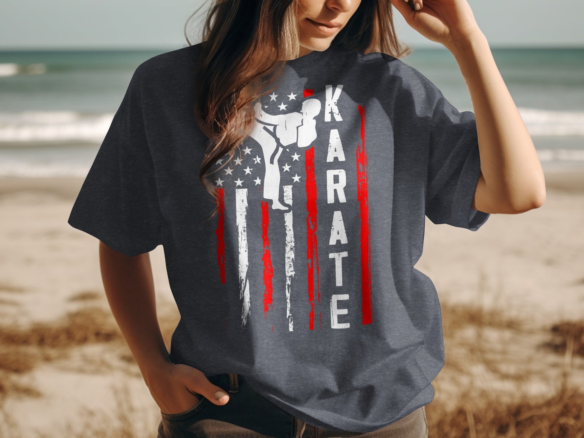 Karate flag design on a dark grey t-shirt worn by a woman on a beach.