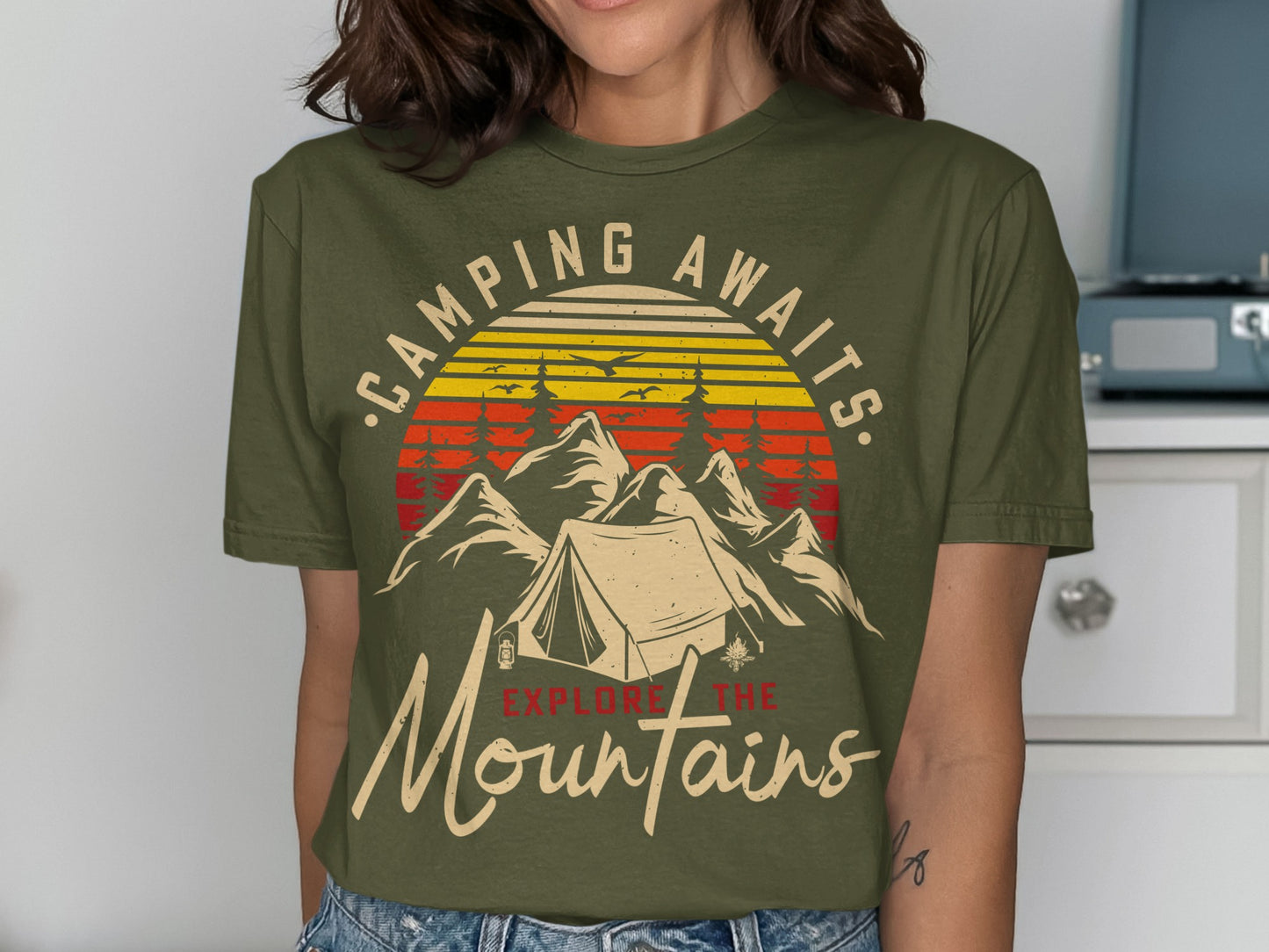 Olive t-shirt with mountains, tent, trees, and text "Camping Awaits Explore the Mountains".