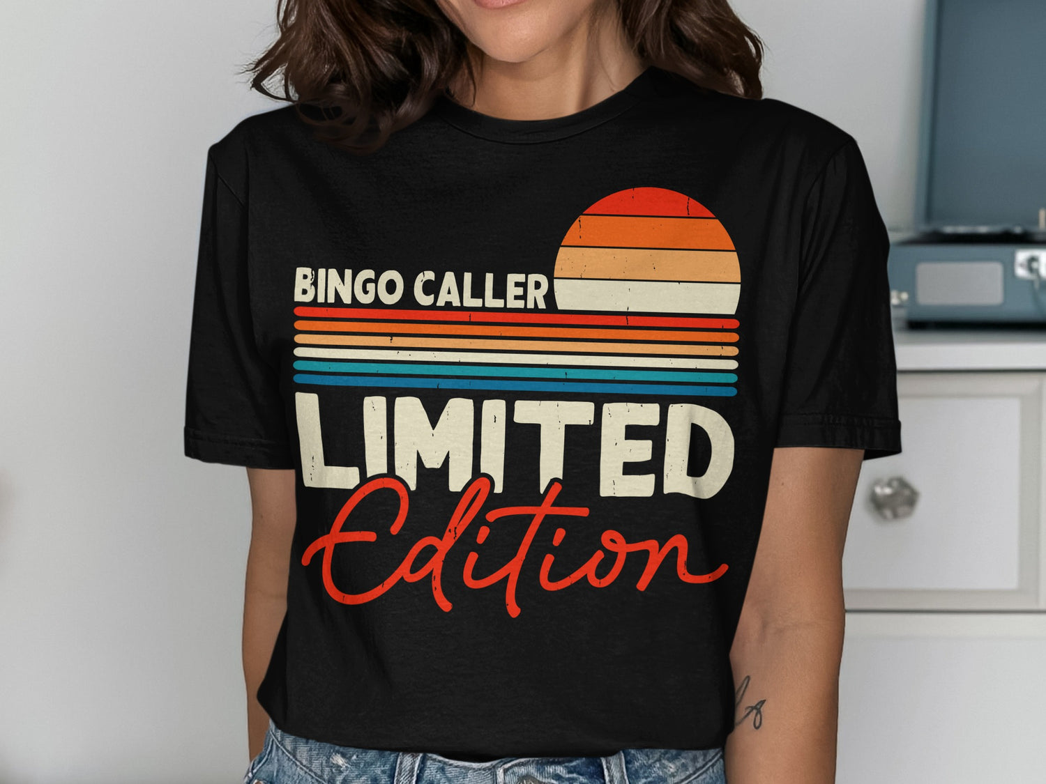 Black t-shirt with "Bingo Caller Limited Edition" and a striped sunset graphic.
