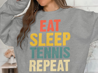 Grey sweatshirt with "Eat Sleep Tennis Repeat" text in red, yellow, and teal.