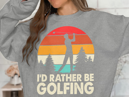 Gray sweatshirt with "I'D RATHER BE GOLFING" text and a sunset graphic.