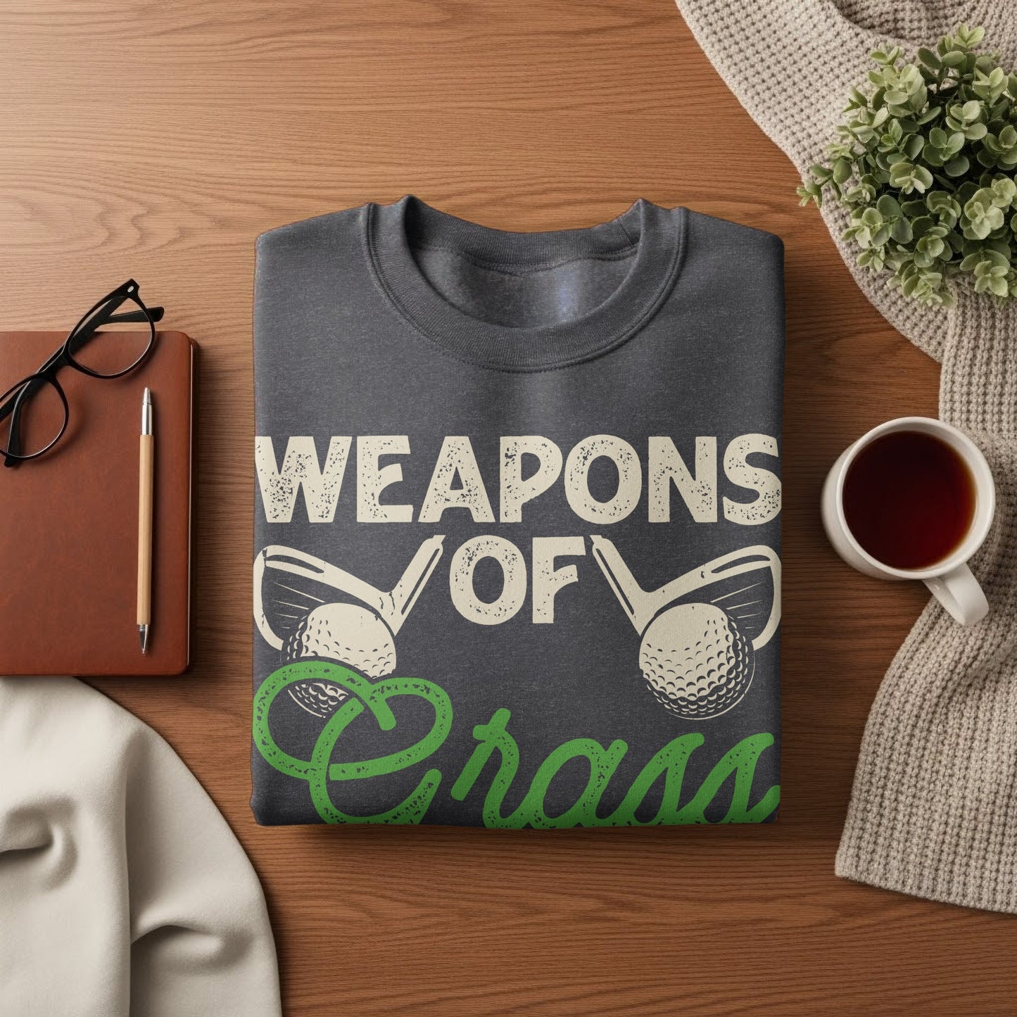 Dark gray t-shirt with "WEAPONS OF GRASS" text and golf imagery.