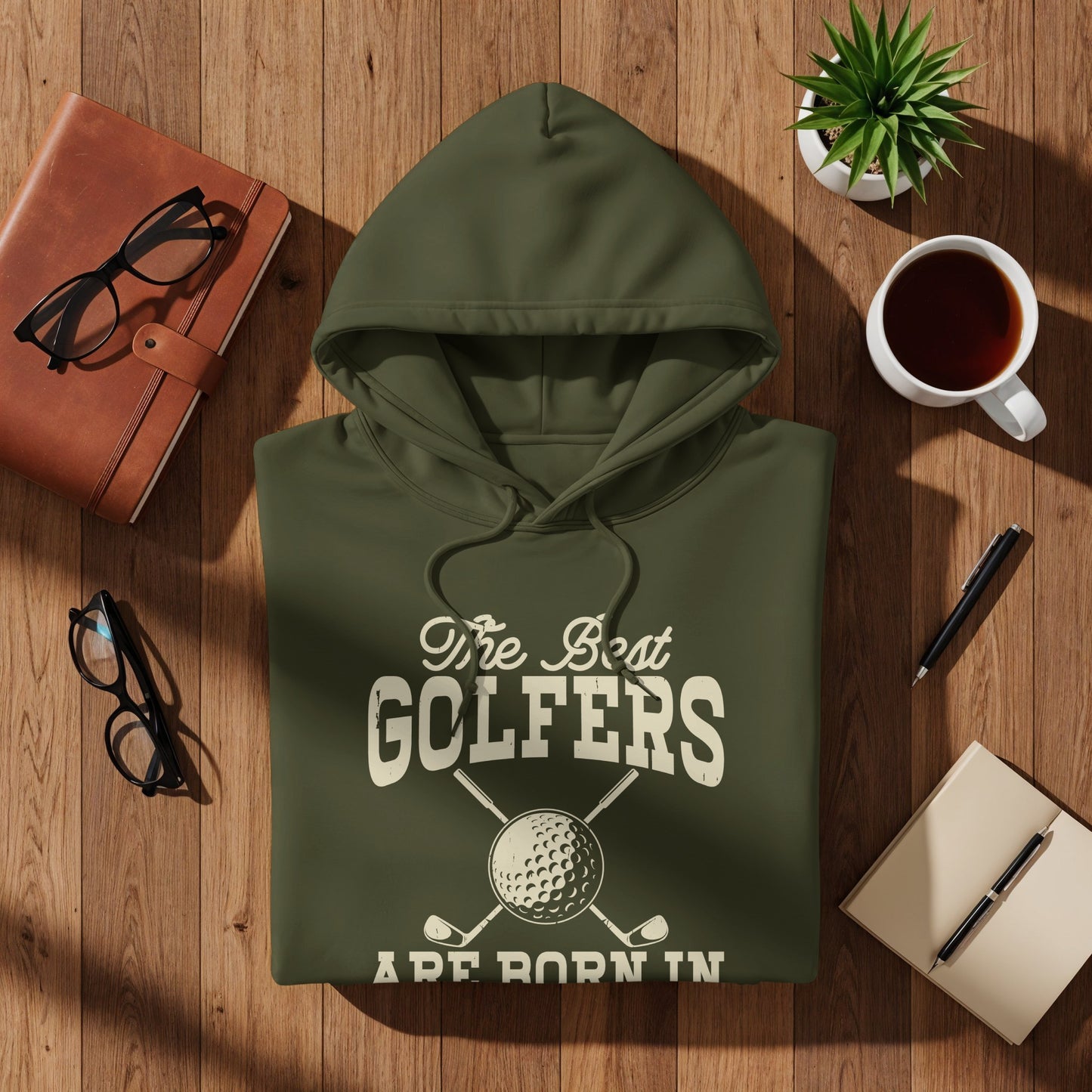 Olive green hoodie with "The Best Golfers Are Born In" and golf club graphic.