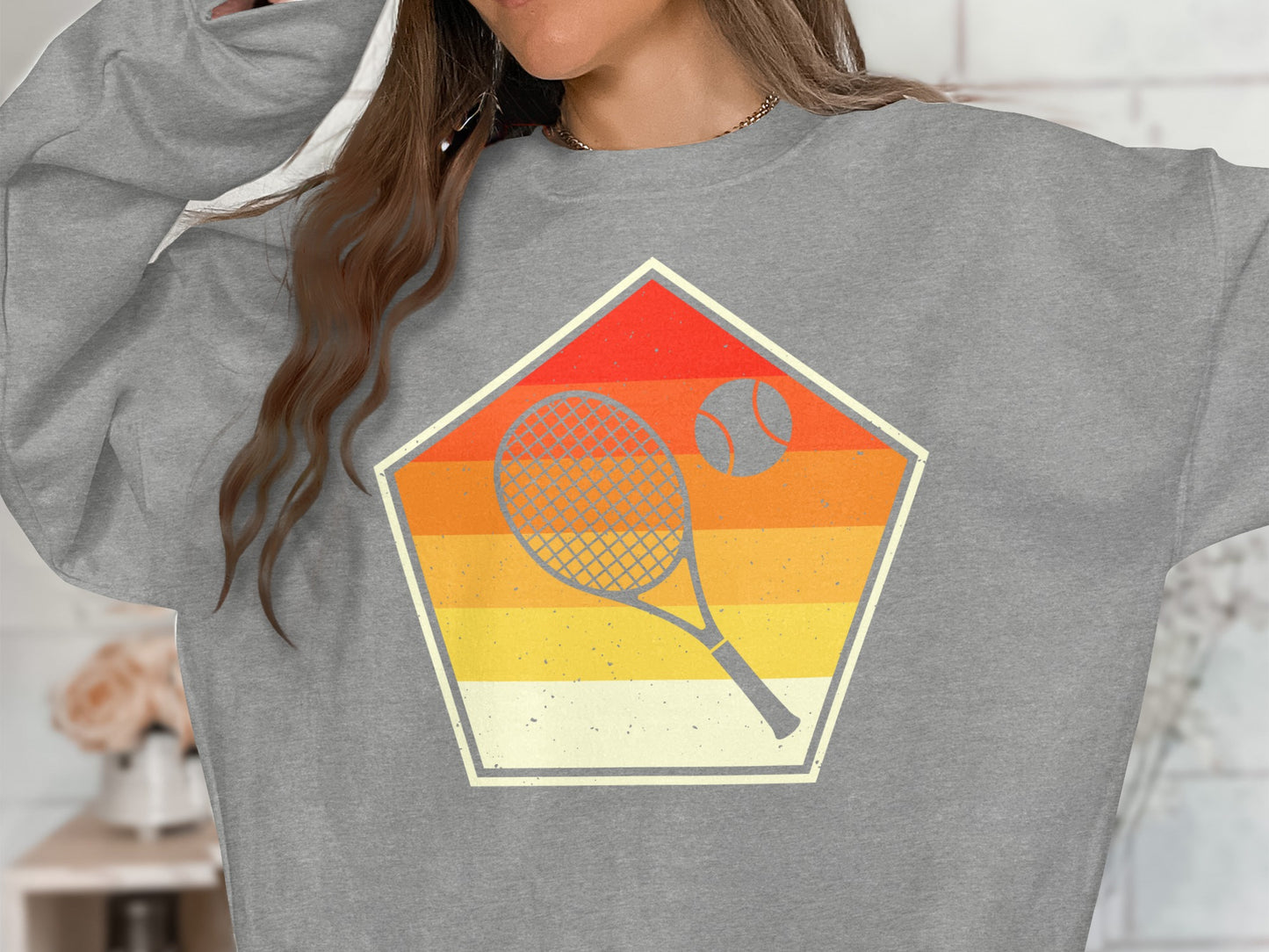 Gray sweatshirt with retro tennis racket and ball graphic inside a pentagon.