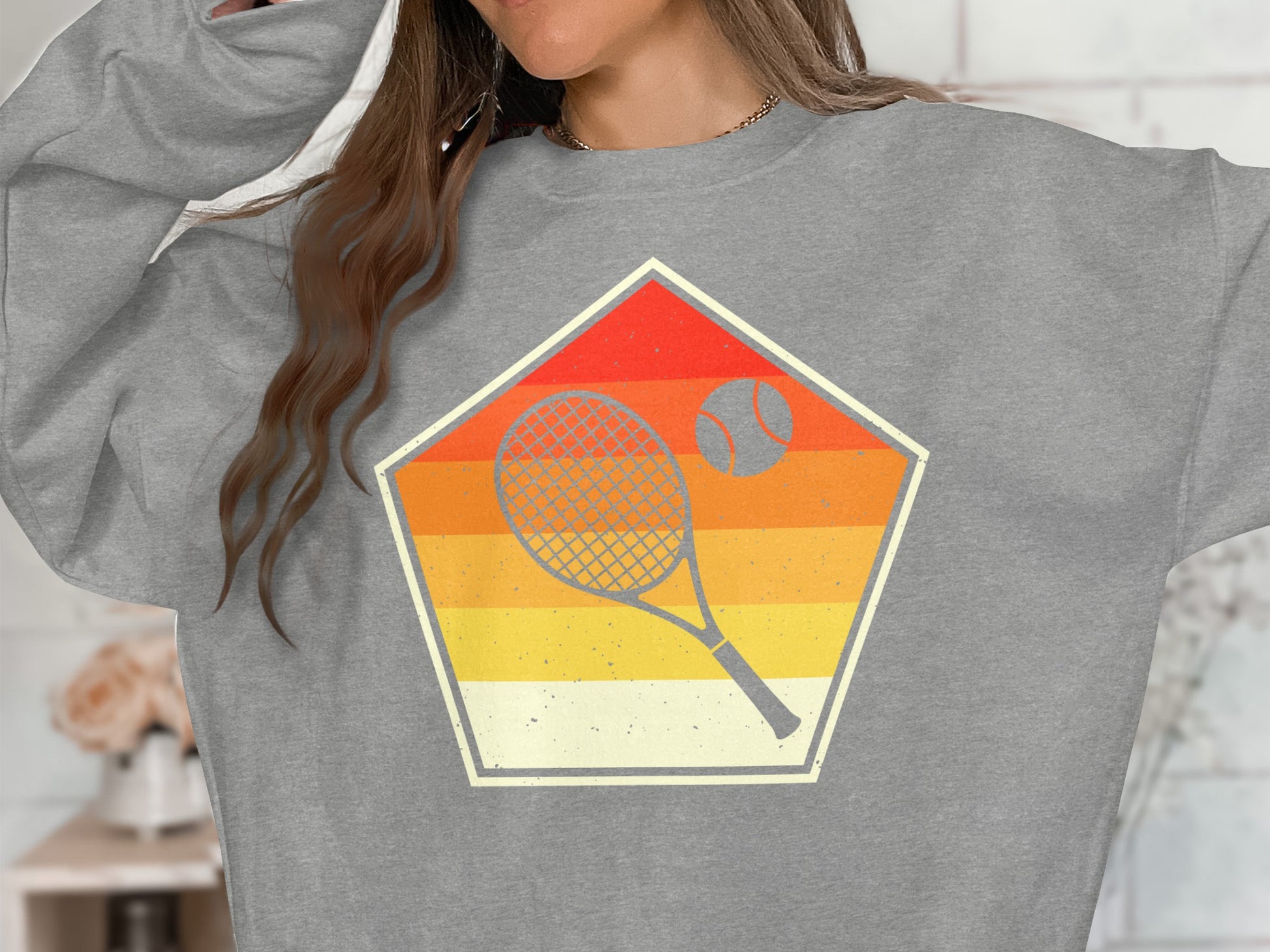 Gray sweatshirt with retro tennis racket and ball graphic inside a pentagon.