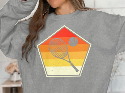 Gray sweatshirt with retro tennis racket and ball graphic inside a pentagon.