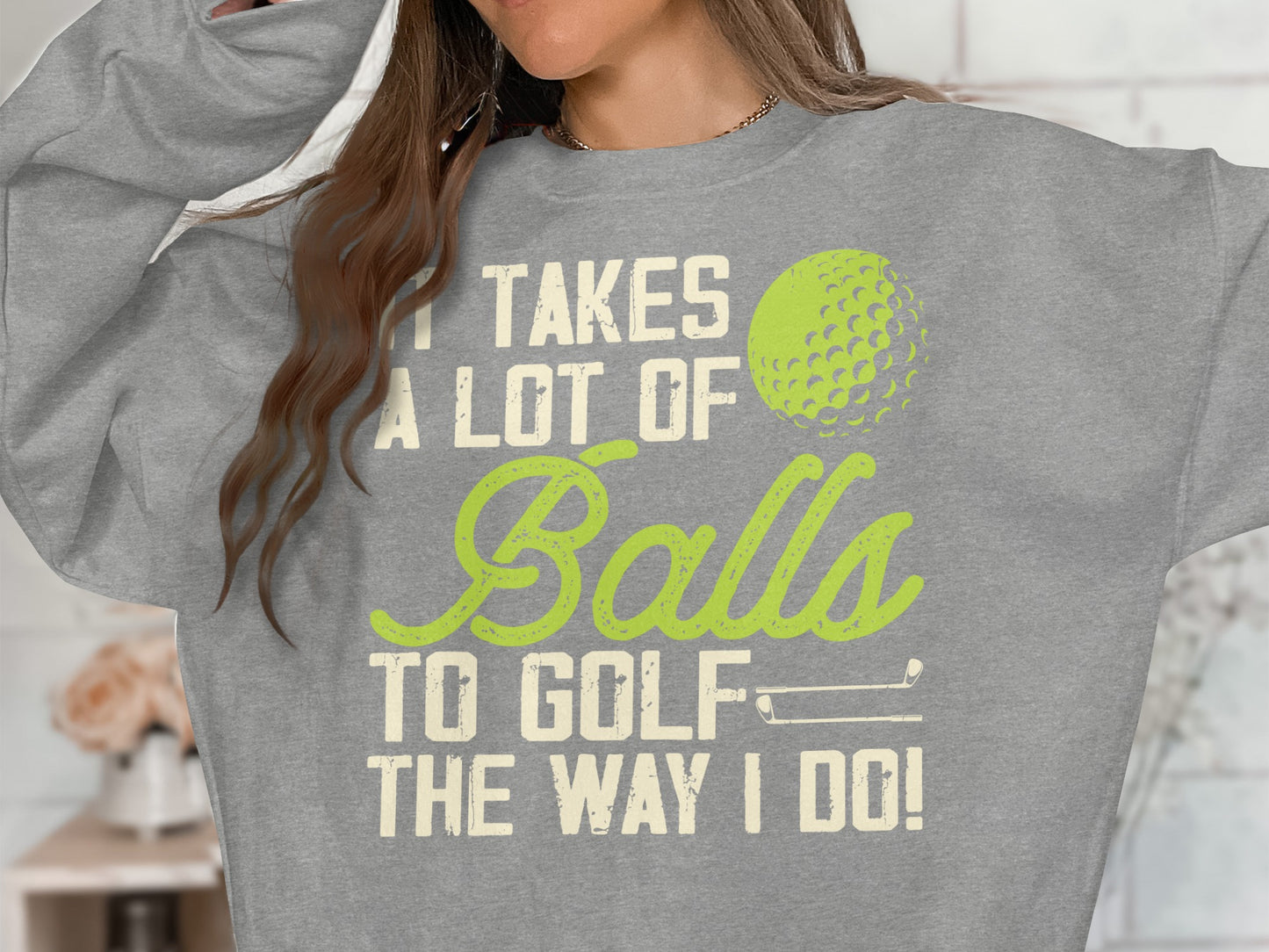 Gray sweatshirt with text "IT TAKES A LOT OF BALLS TO GOLF THE WAY I DO!"