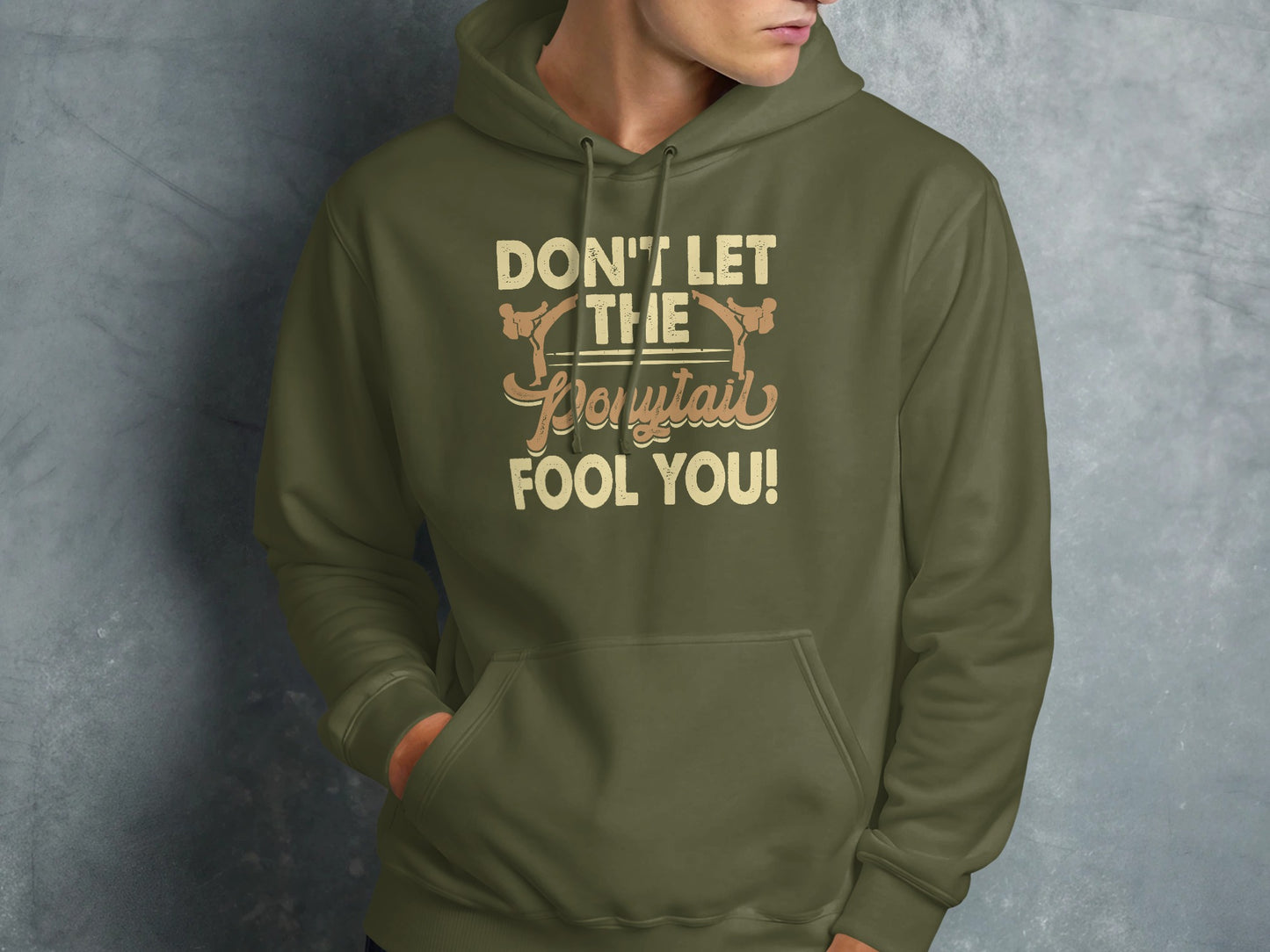 Olive green hoodie with "Don't let the ponytail fool you!" text.