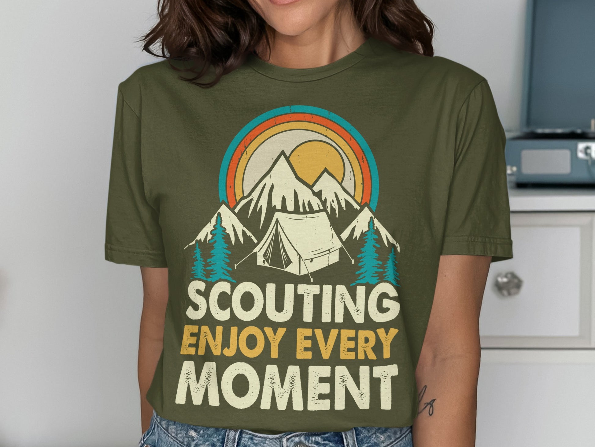 Olive green t-shirt with mountains, tent, sun, and "Scouting Enjoy Every Moment" text.