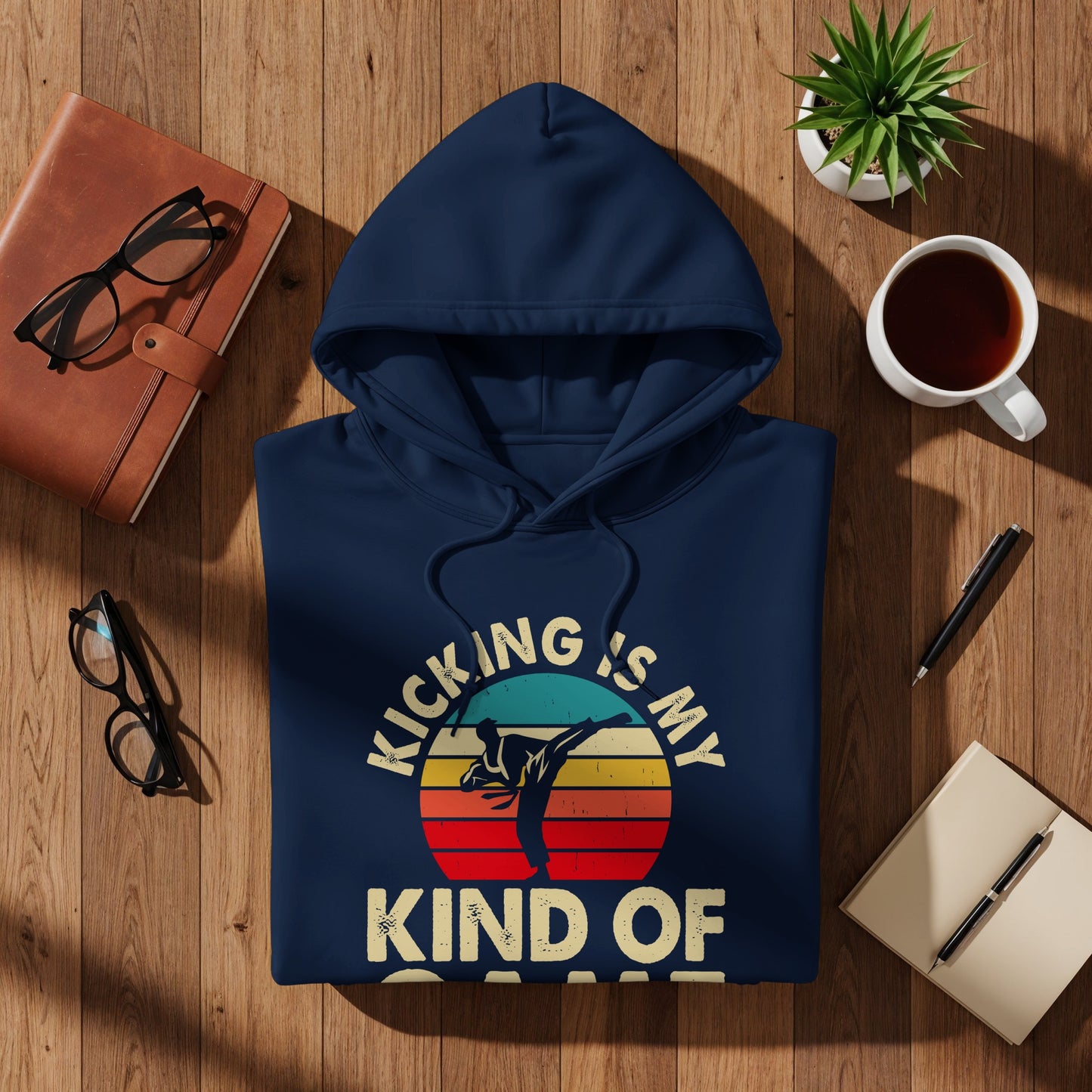 Navy hoodie with "Kicking is my kind of sport" text and sunset graphic.