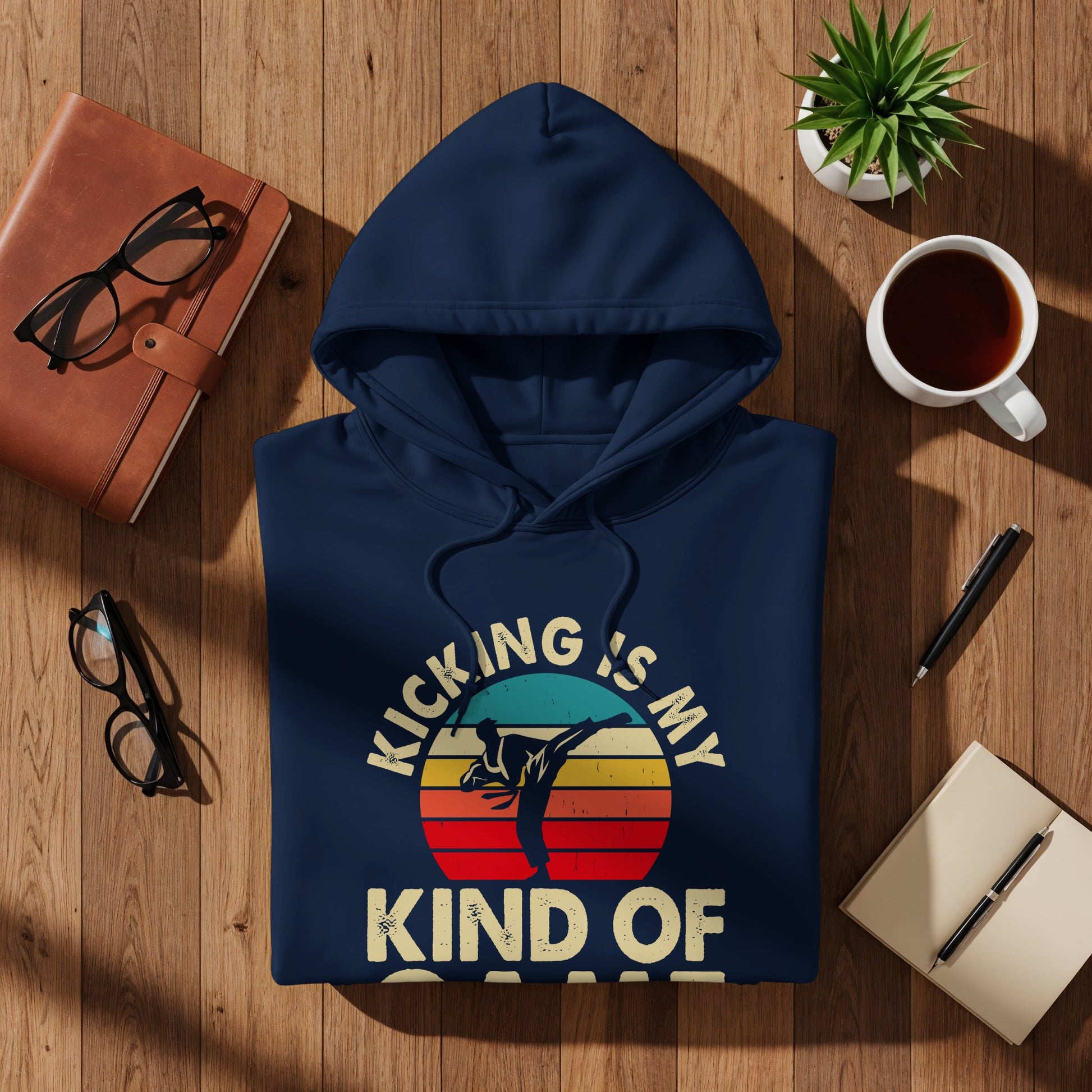 Navy hoodie with "Kicking is my kind of sport" text and sunset graphic.