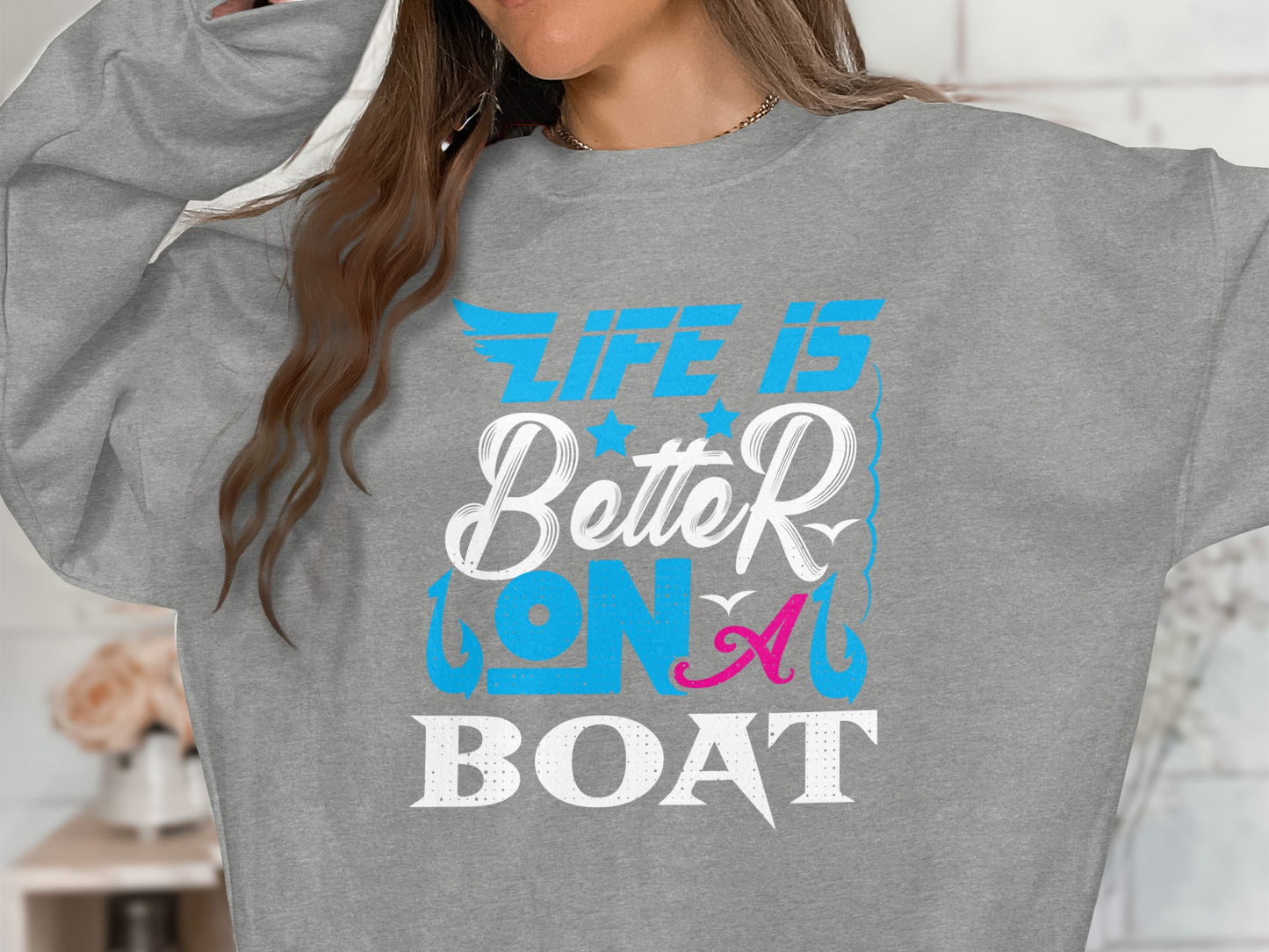 Grey sweatshirt with "Life is Better on a Boat" graphic in blue and pink.