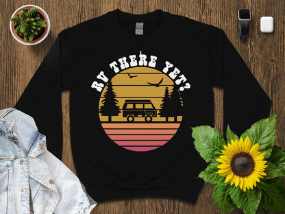 Black sweatshirt with retro sunset graphic, van, trees, and birds, "BY HERE YET?"