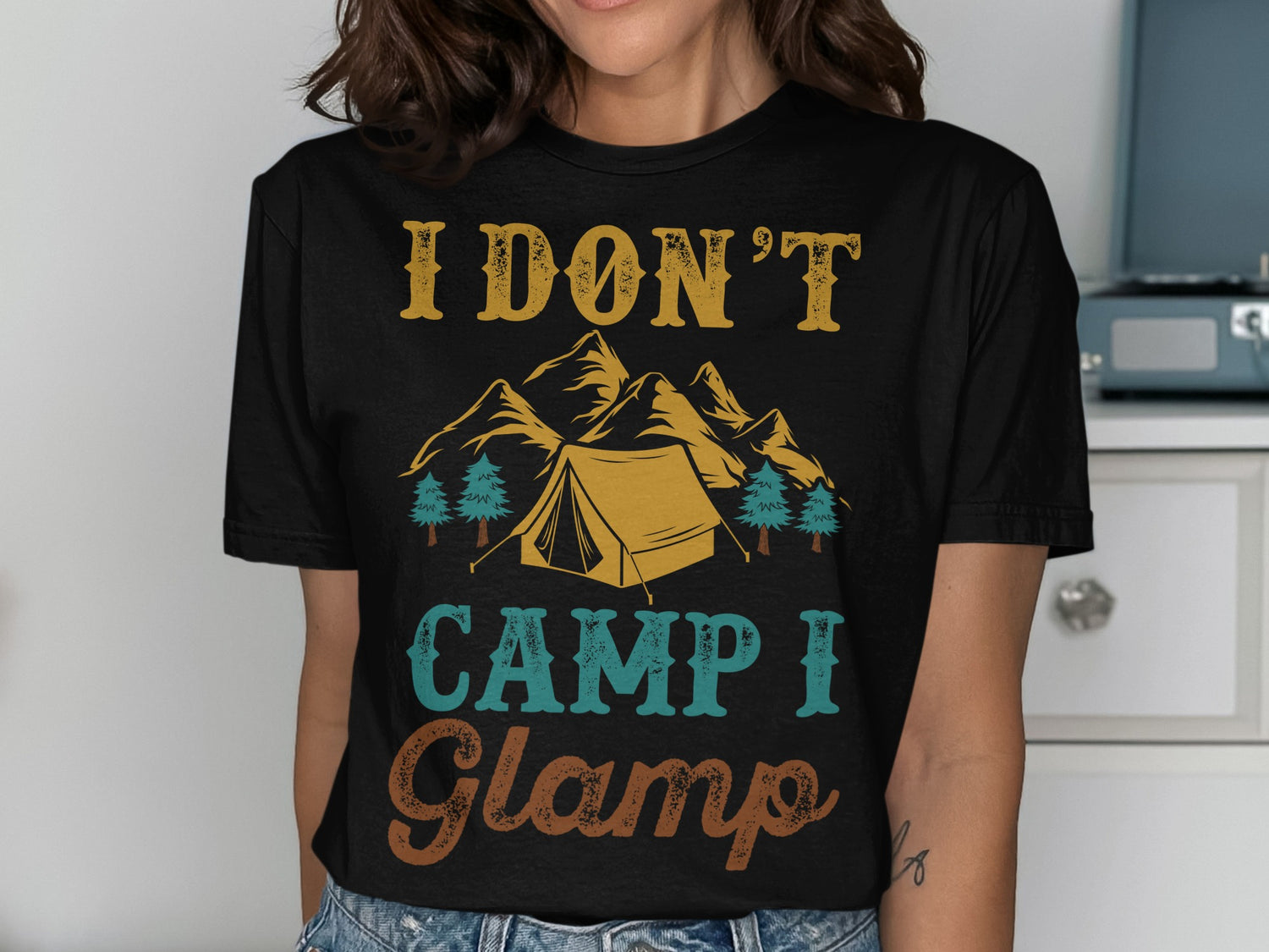 T-shirt with text "I don't camp I glamp" and a mountain scene.