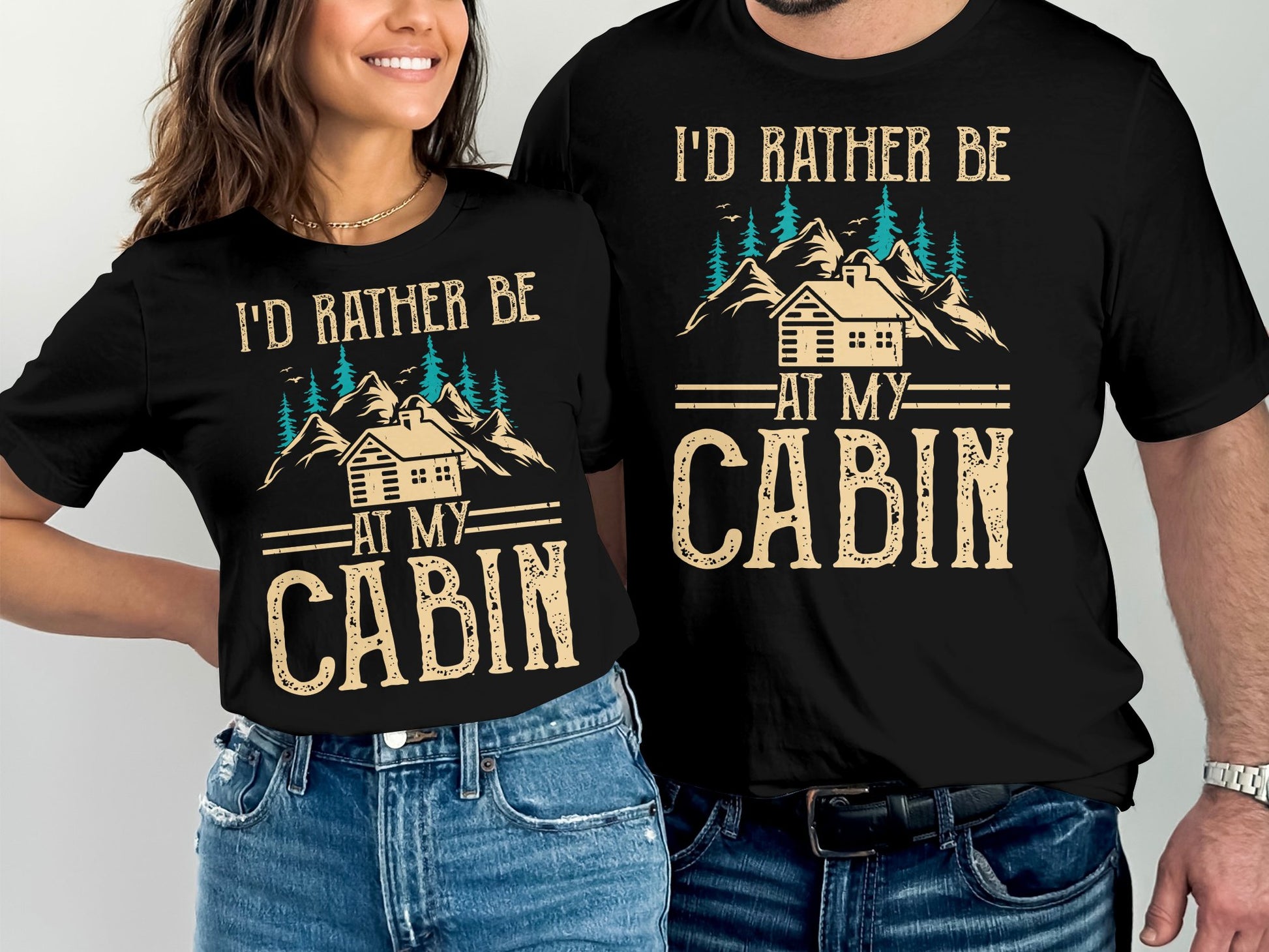 Two t-shirts with "I'd Rather Be At My Cabin" text and mountain graphic.