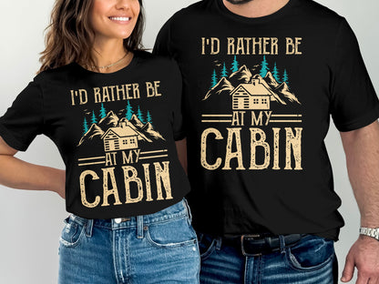 Two t-shirts with "I'd Rather Be At My Cabin" text and mountain graphic.